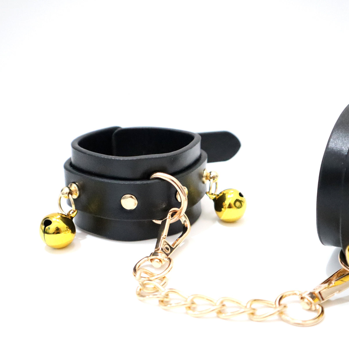 Gold-tone bells, D-ring and chain detail on black PU wrist cuff