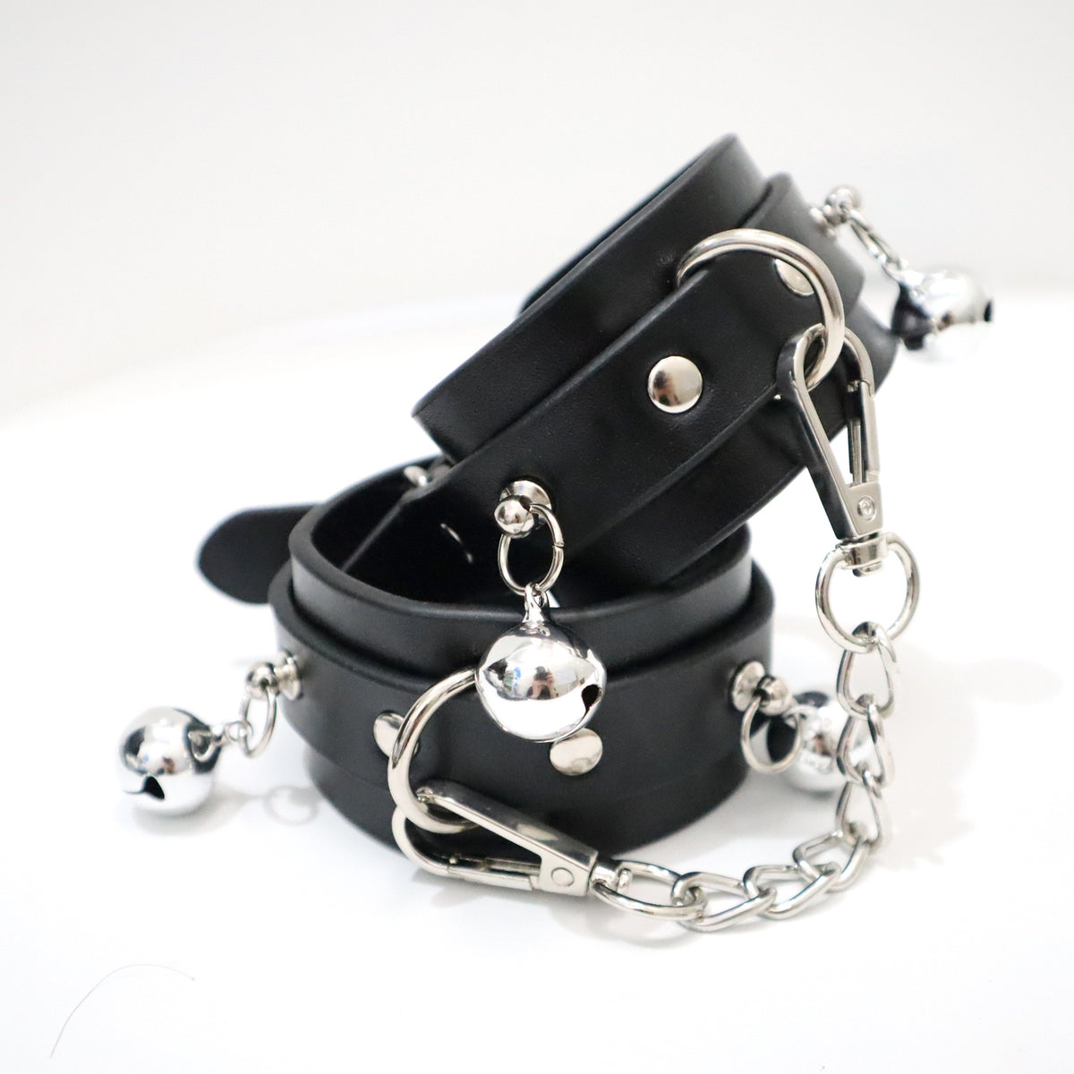 Silver-tone bell wrist cuffs with adjustable straps and removable chain